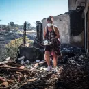 Μια γυναίκα σε απόγνωση μαζεύει μέσα από τα αποκαΐδια του σπιτιού της στο Κρυονέρι Αττικής κάποια σερβίτσια που σώθηκαν. 