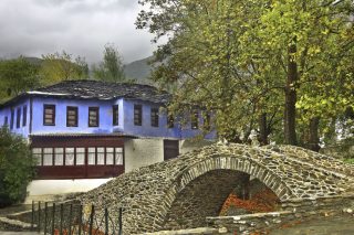 Το παραδοσιακό πέτρινο γεφύρι και το περίφημο «Μπλε Σπίτι» στη Μουσθένη (φωτ.: Ηρακλής Μήλας)