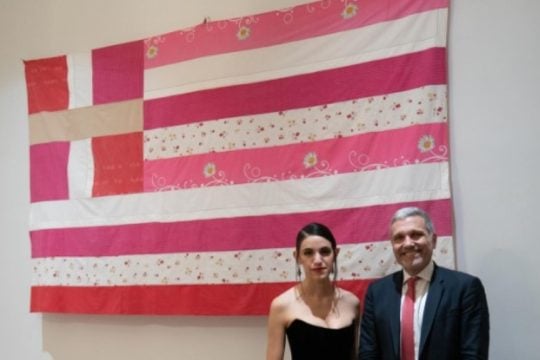 η καλλιτέχνις με τον πρόξενο μπροστά στη σημαία