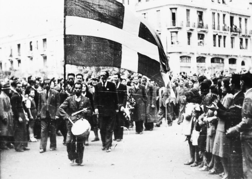 Τμήματα ανταρτών με τεράστιες ελληνικές και συμμαχικές σημαίες προσέρχονται για την εορταστική εκδήλωση