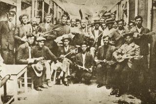 Ρεμπέτες στον Πειραιά το 1933. Ο Βαμβακάρης διακρίνεται όρθιος αριστερά κρατώντας μπουζούκι