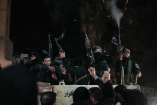 members of the new security forces, primarily fighters from Hayat Tahrir al-Sham (HTS), fire into the air in celebration in Homs, Syria