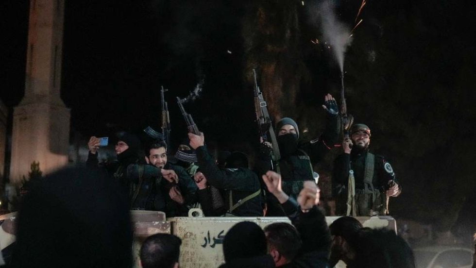 members of the new security forces, primarily fighters from Hayat Tahrir al-Sham (HTS), fire into the air in celebration in Homs, Syria