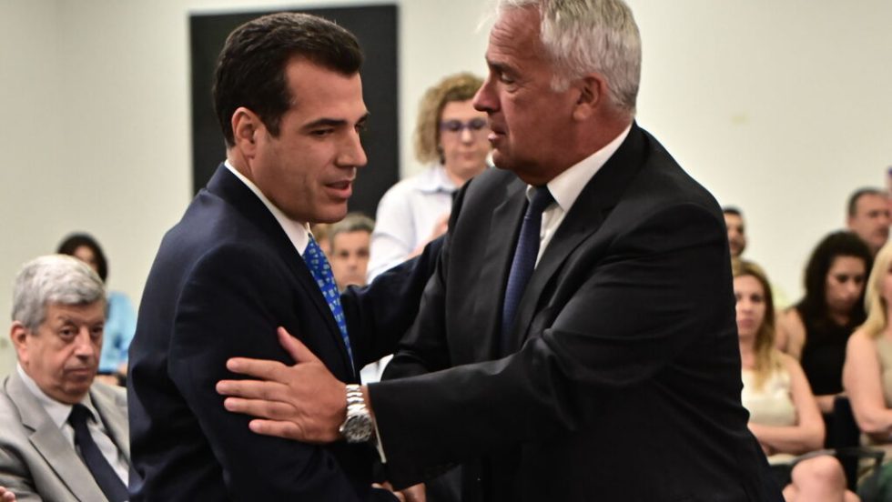 O Μάκης Βορίδης (δεξιά) καλωσορίζει τον διάδοχό του Θάνο Πλεύρη στο υπουργείο Μετανάστευσης και Ασύλου
