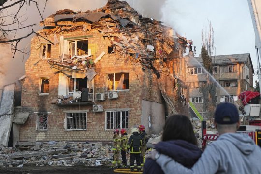 Προφανώς δεν πρόκειται για στρατιωτικό στόχο. Ζευγάρι κατοίκων του Κιέβου βλέπει πυροσβέστες εν δράσει στα καπνίζοντα ερείπια ενός σπιτιού στο κέντρο της πρωτεύουσας της Ουκρανίας.