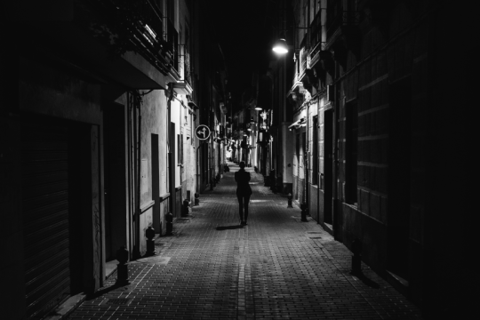Ανδρας περπατάει σε δρόμο πόλης τη νυχτα