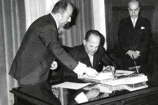8 Οκτωβρίου 1973. Ο Μαρκεζίνης παρακολουθεί υπομονετικά την προσυπογραφή του πρακτικού της ορκωμοσίας του ως «δοτού» πρωθυπουργού από τον δικτάτορα Παπαδόπουλο