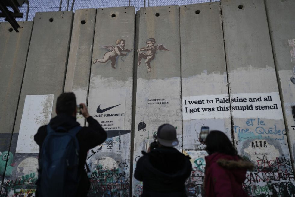 Εργο του Banksy στο τείχος της Δυτικής Οχθης που έχει υψώσει το Ισραήλ στην κατεχόμενη Παλαιστίνη απαθανατίζουν περαστικοί